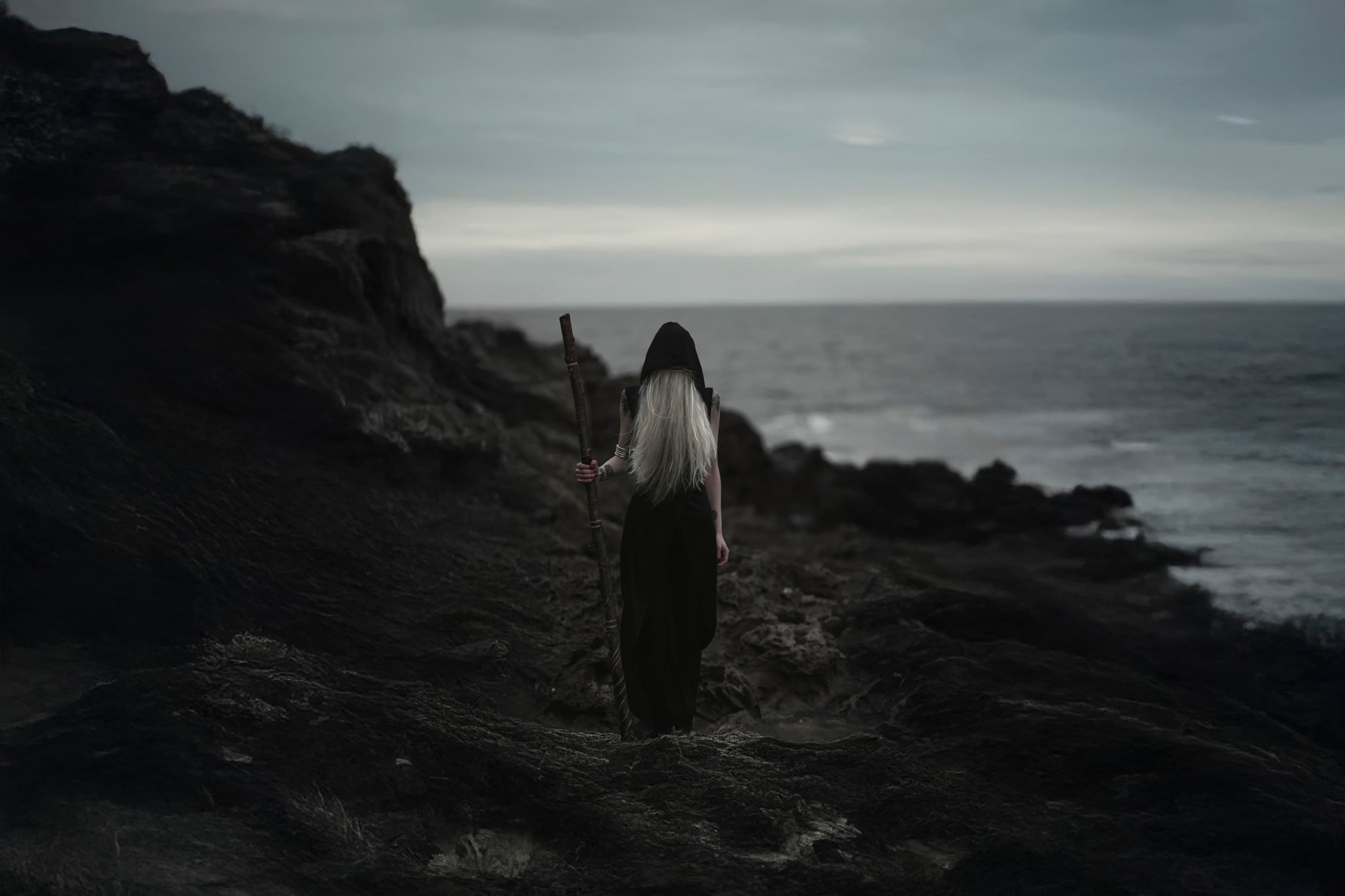 A figure facing the ocean from a rocky shore