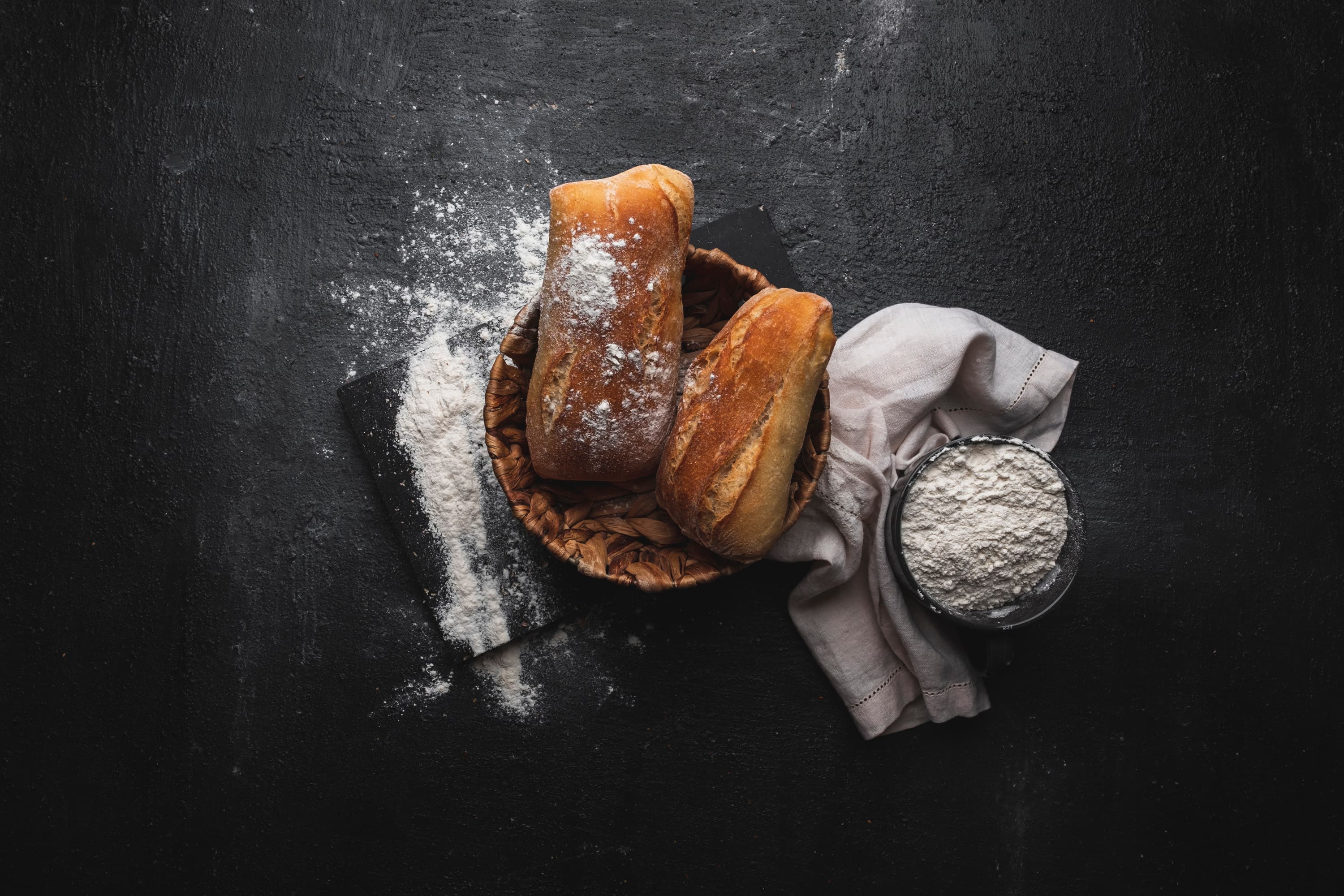 Rustic bread and flour on a dark slate surface