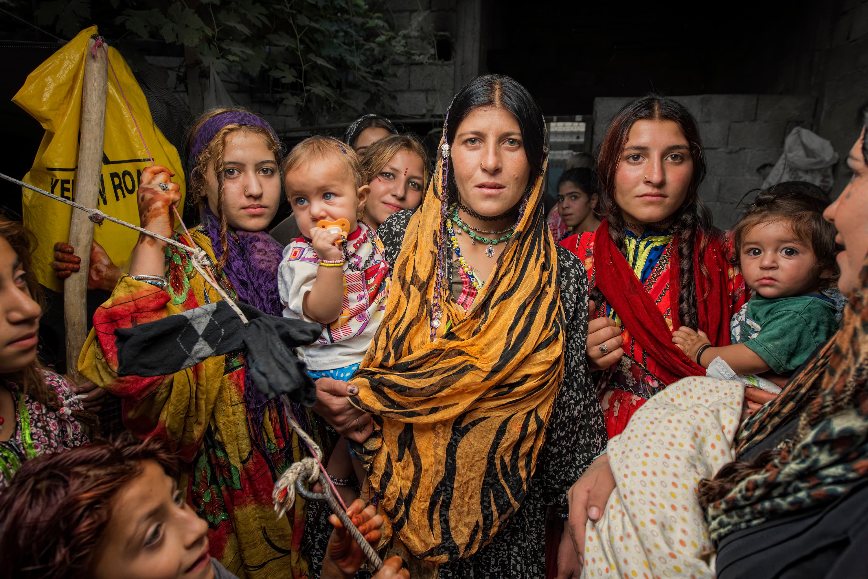 A group of women and children looking at the camera in an improvised shelter