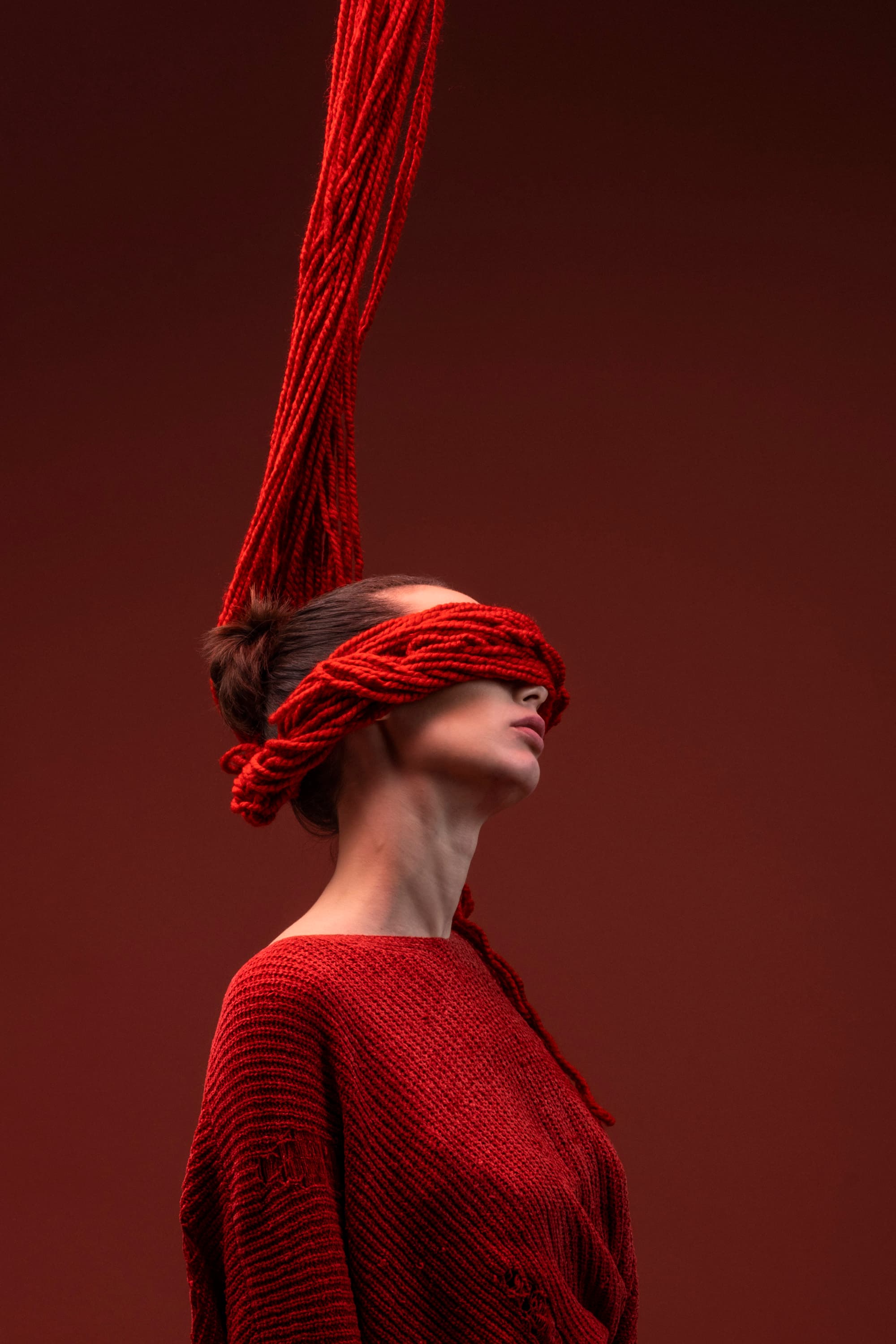 A figure in red knitwear with red threads extending above the head