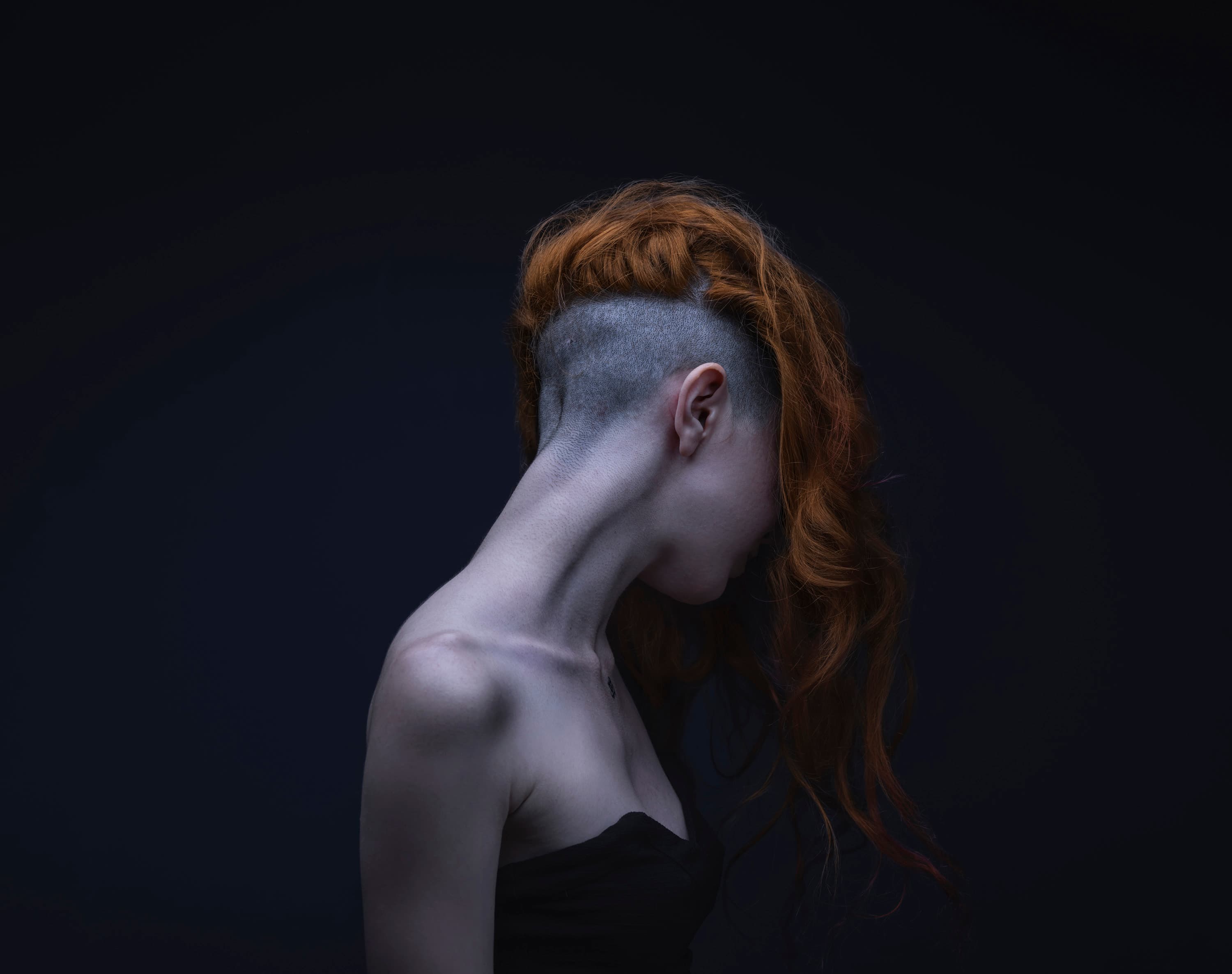 A sculptural portrait with violet light against a dark background